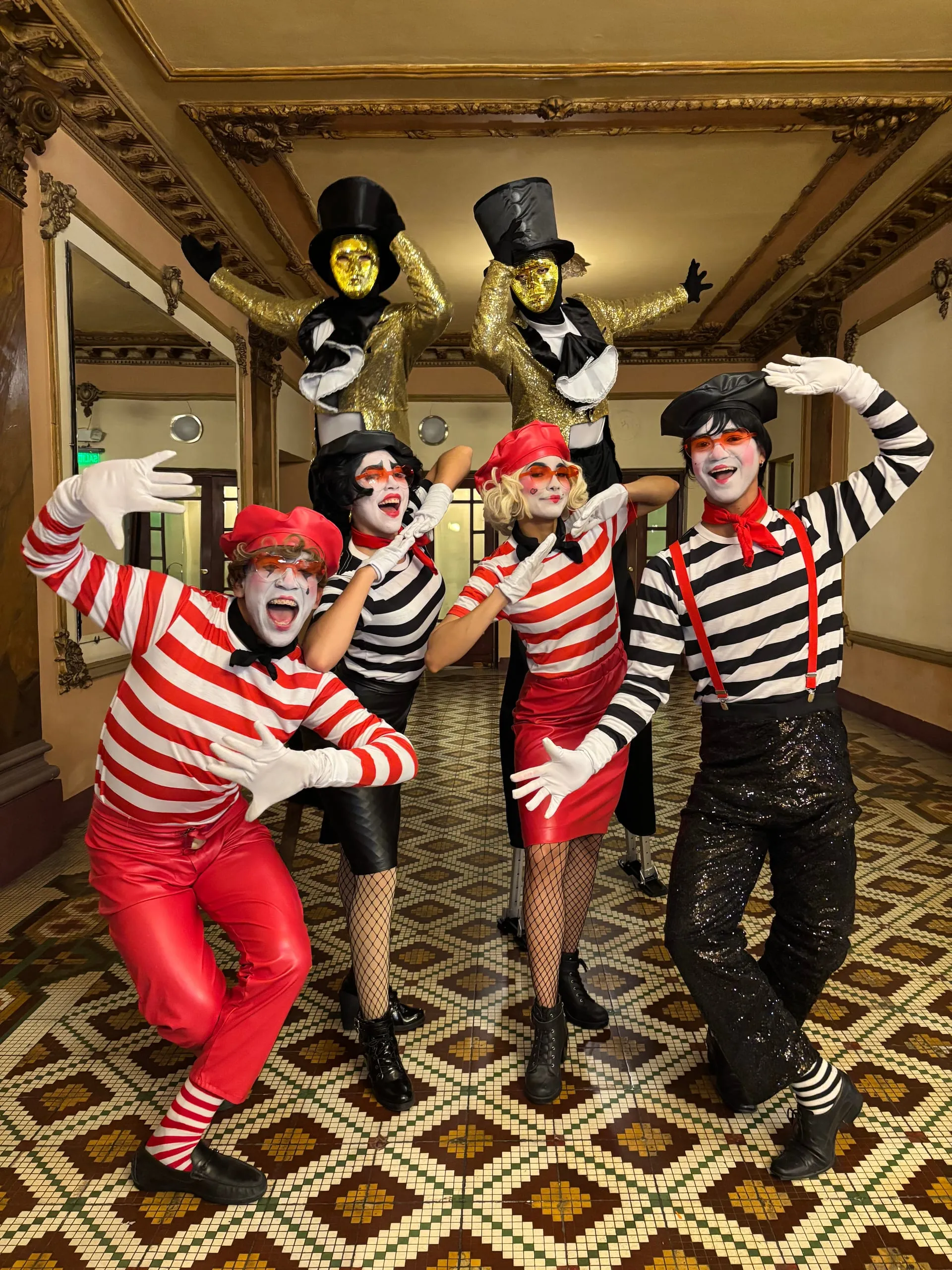 Mimos con trajes de rayas rojas y negras recibiendo a los invitados