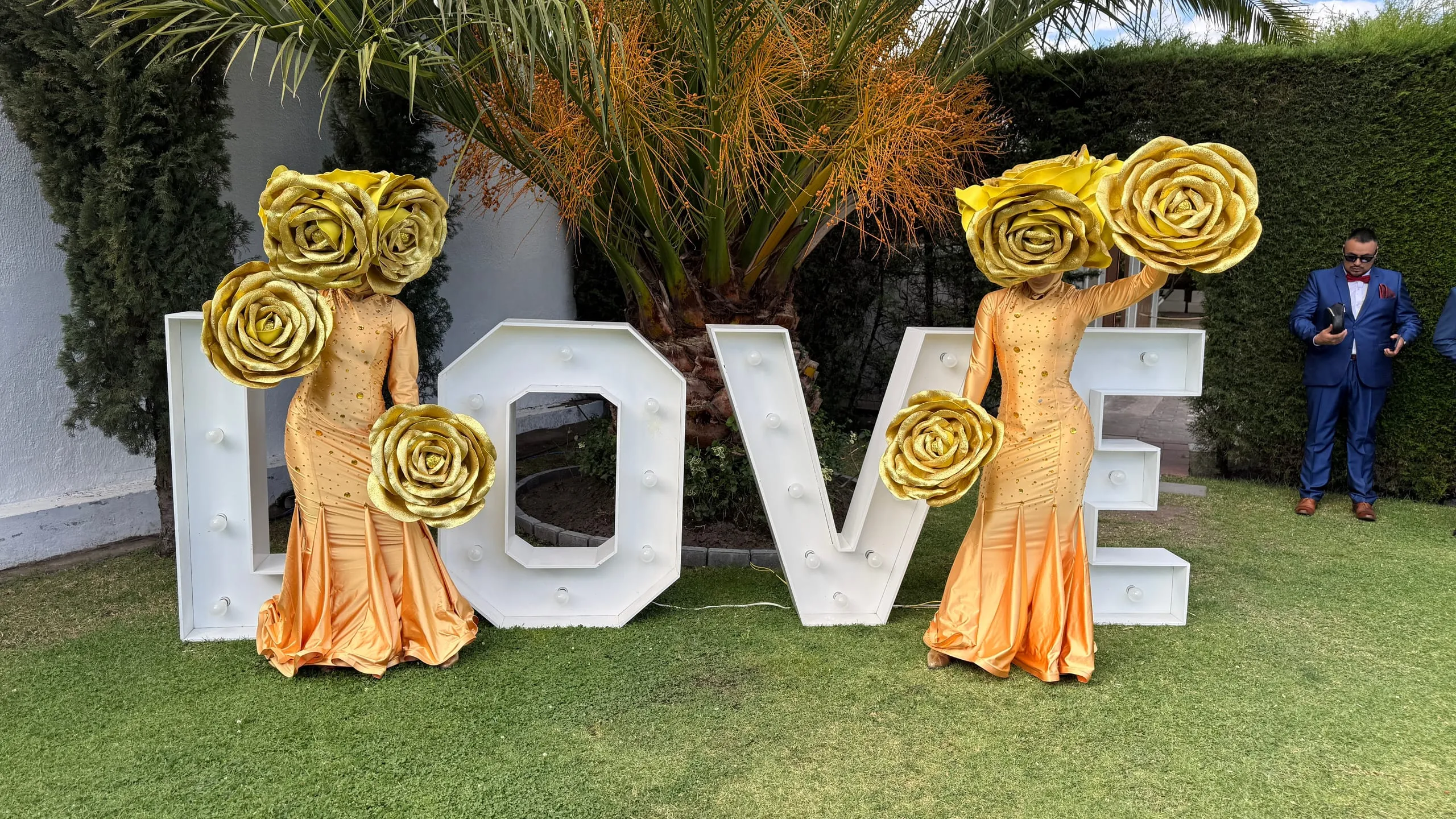 Personajes con cabeza de rosas doradas junto a letras LOVE
